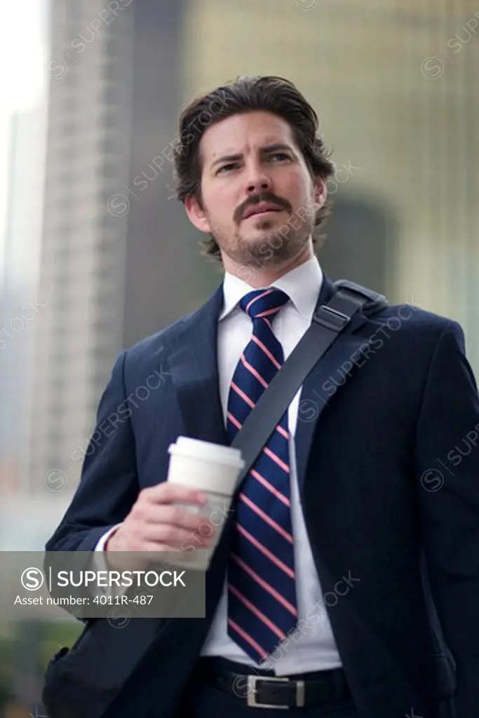 Businessman with coffee cup in street