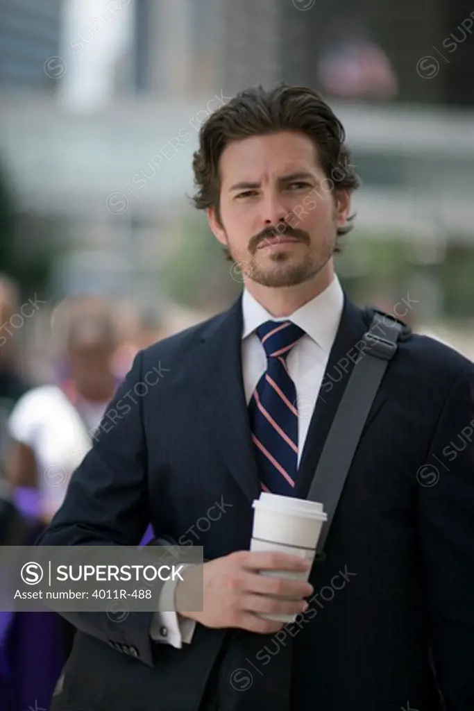 Portrait of businessman with coffee cup in street