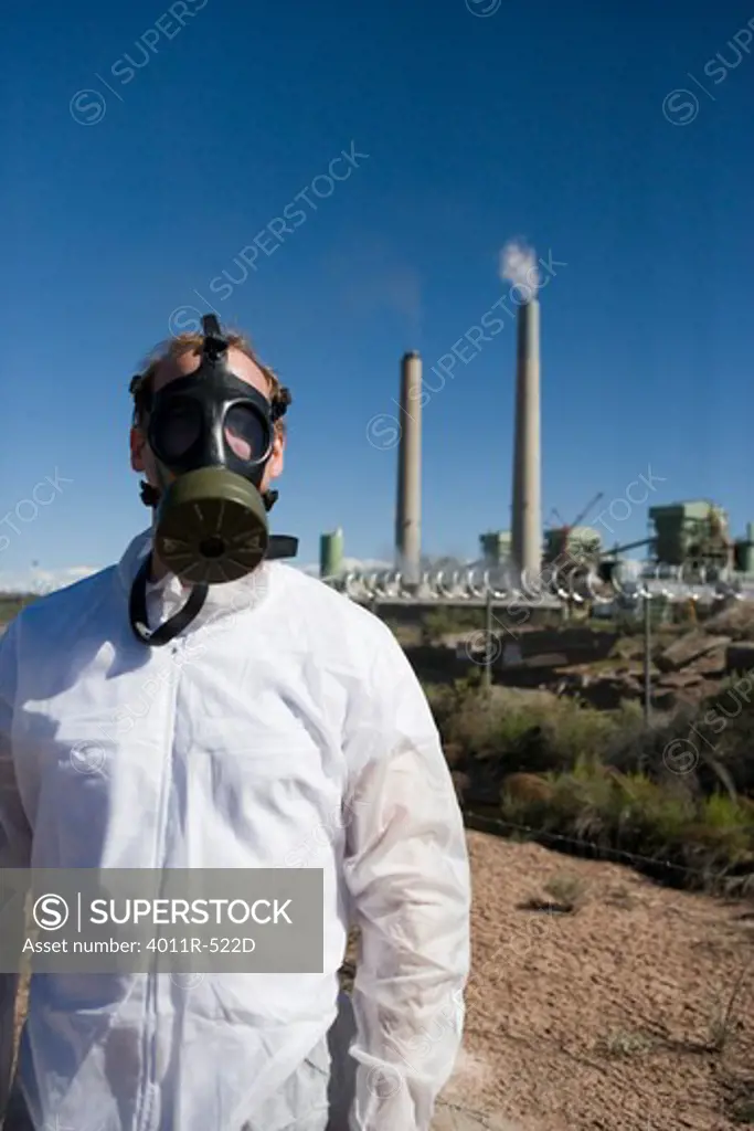 Man wearing gas mask in front of coal mine refinery
