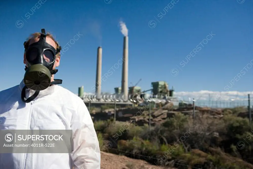 Man wearing gas mask in front of coal mine refinery