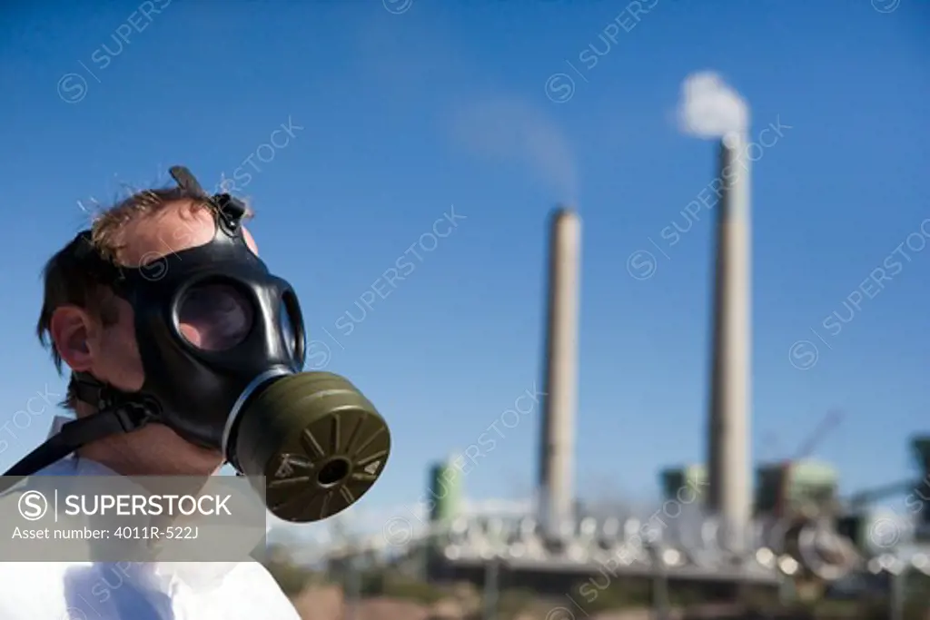 Man in gas mask in front of coal mine refinery