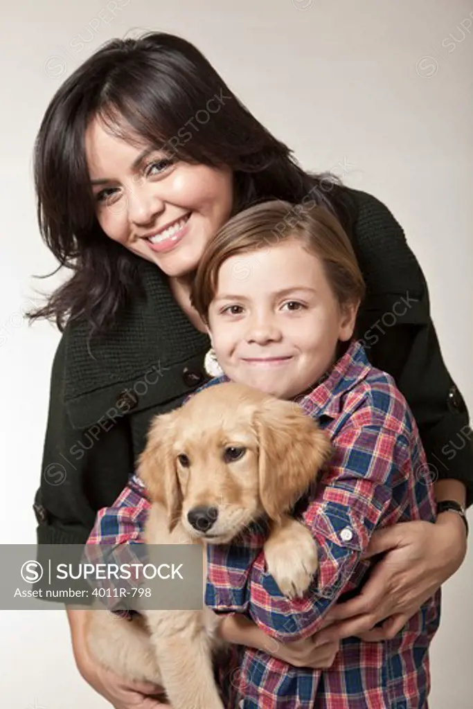 Studio portrait of woman with son holding puppy