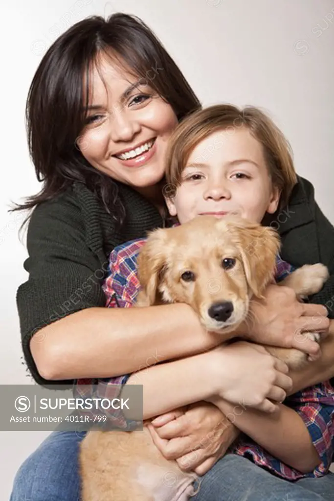 Studio portrait of woman with son holding puppy