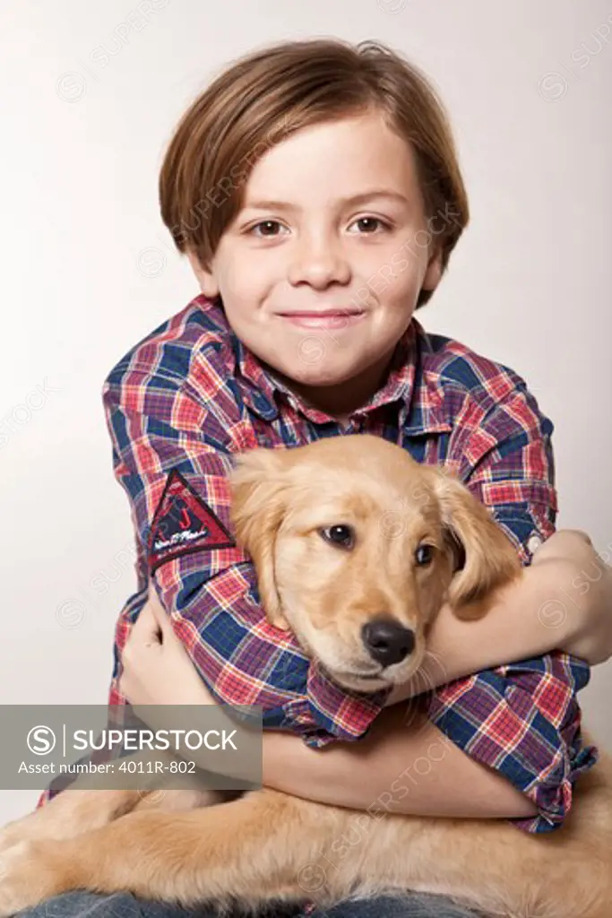 Studio portrait of smiling boy hugging puppy