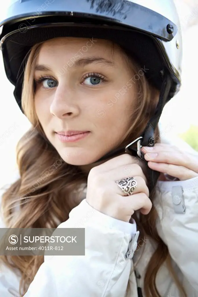 Portrait of teenage girl fastening helmet