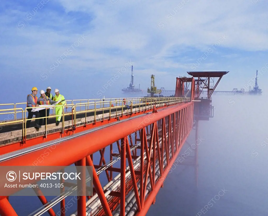 Two oil foremen with workers standing on oil rig walkway