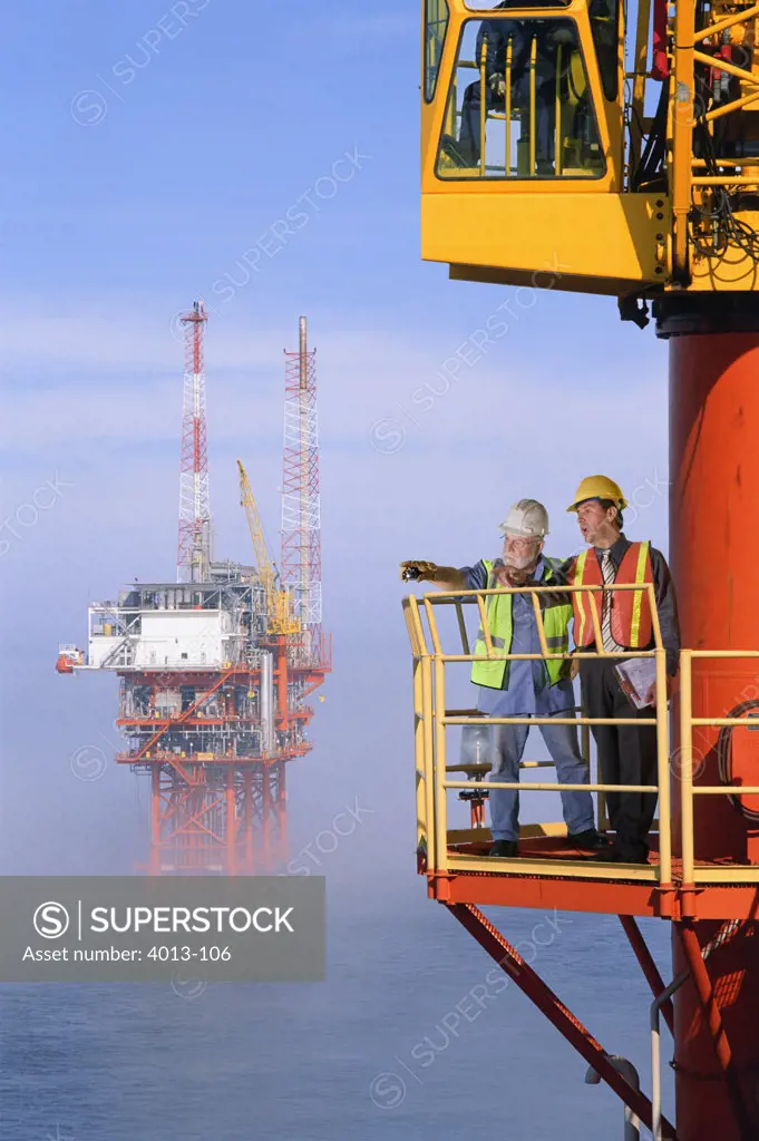 Two oil foremen standing on an oil rig platform
