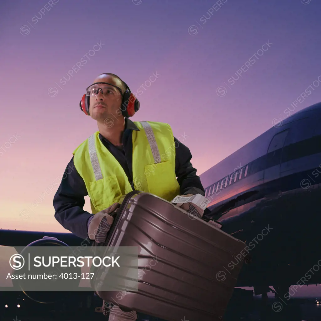 Airport baggage employee loading luggage in an airplane