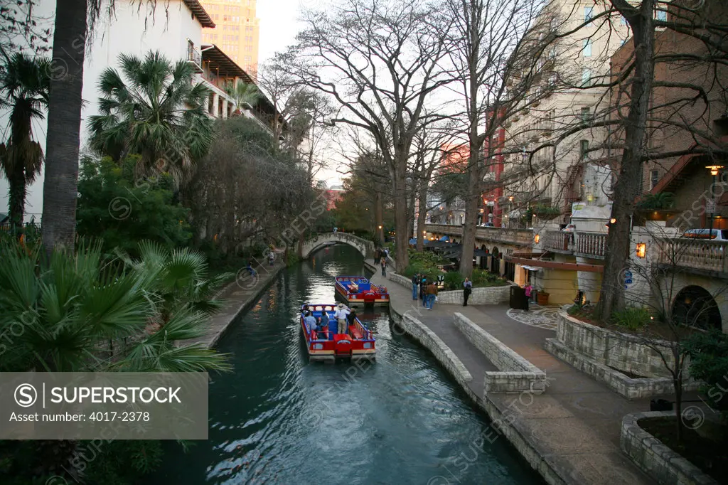 Looking Down the San Antonio Riverfront with Rio San Antonio Cruises River Tour Boats on the water and Poeple on the Riverwalk