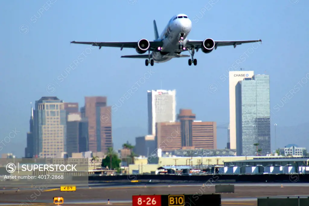 Airplane flying in the sky with skyscraper in the background, Sky Harbor International Airport, Phoenix, Arizona, USA