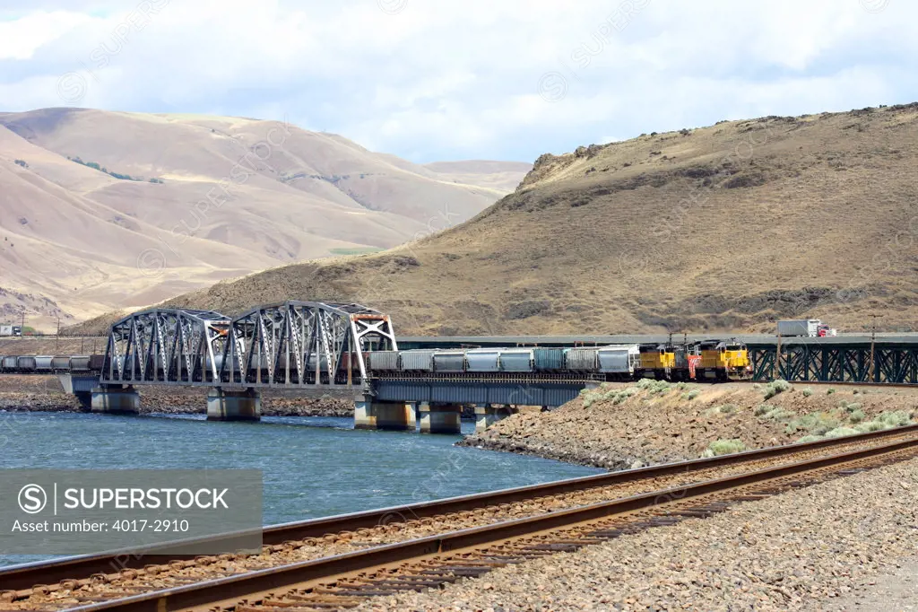 Freight Train crossing the Columbia River heading toward Portland, Oregon with the Cascade Range in distance, USA