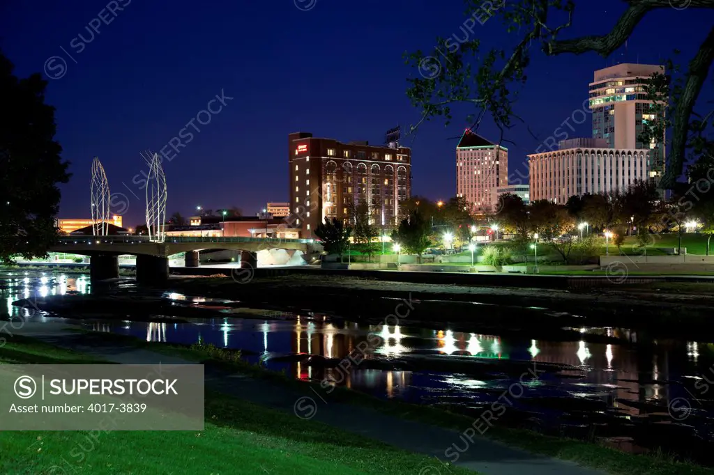 USA, Kansas, Wichita, Skyline along waterfront of Arkansas River at dusk
