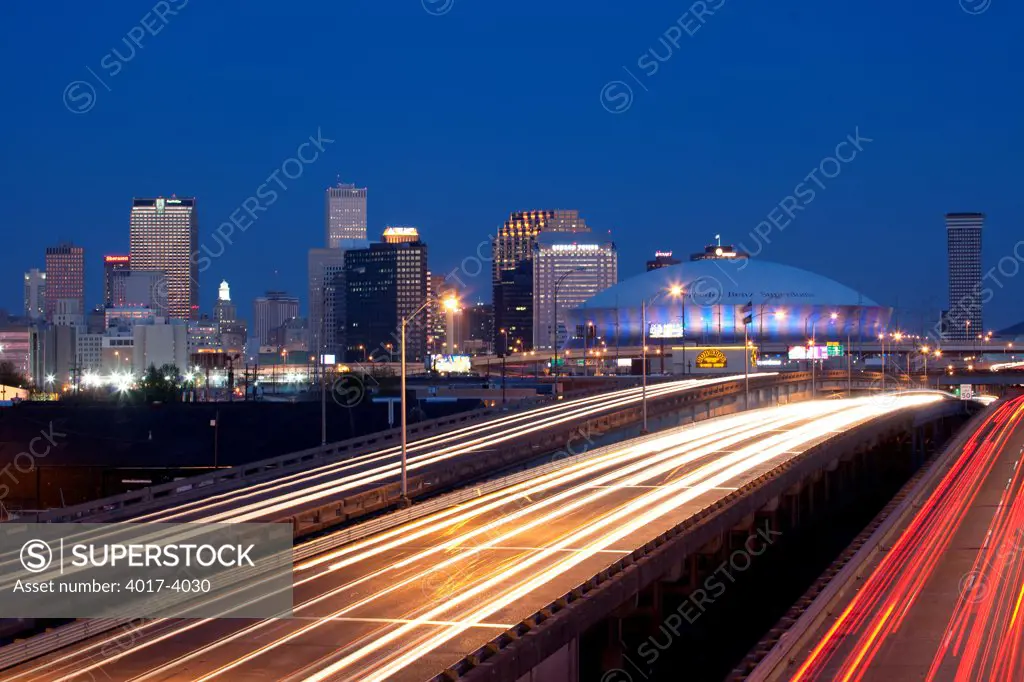 View of the Downtown New Orleans Skyline from I-10 at night with flowing trafic on the highway