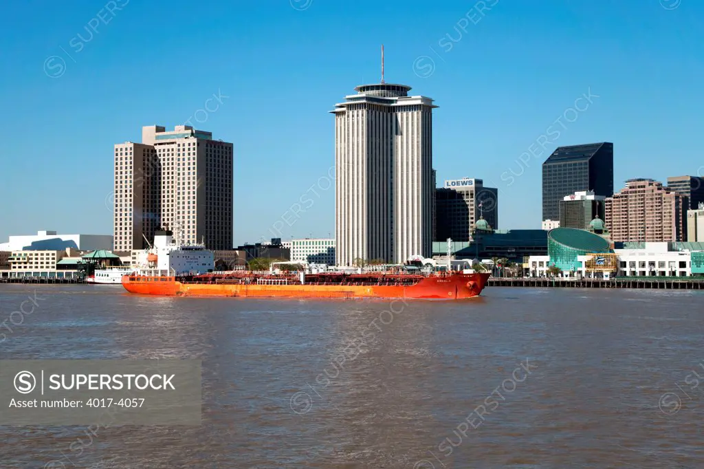 A barge passing through the ports of New Orleans on the Mississippi River with the skyline in the background