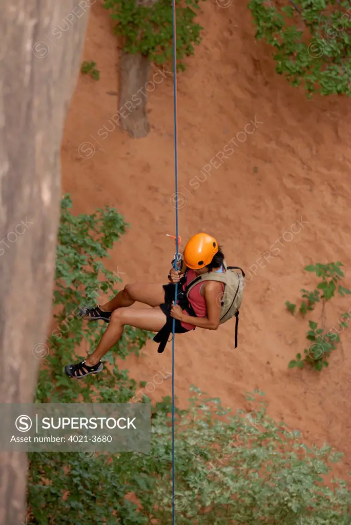 Tourist hanging from a rope while canyoning in the area of the Slickrock Trail, Arches National Park, Moab, Utah, USA