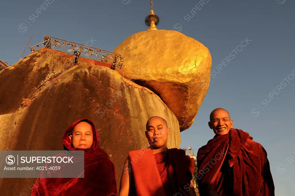 Three monks standing before the pagoda on golden rock, Kyaiktiyo Pagoda, Kyaikto, Mon State, Myanmar