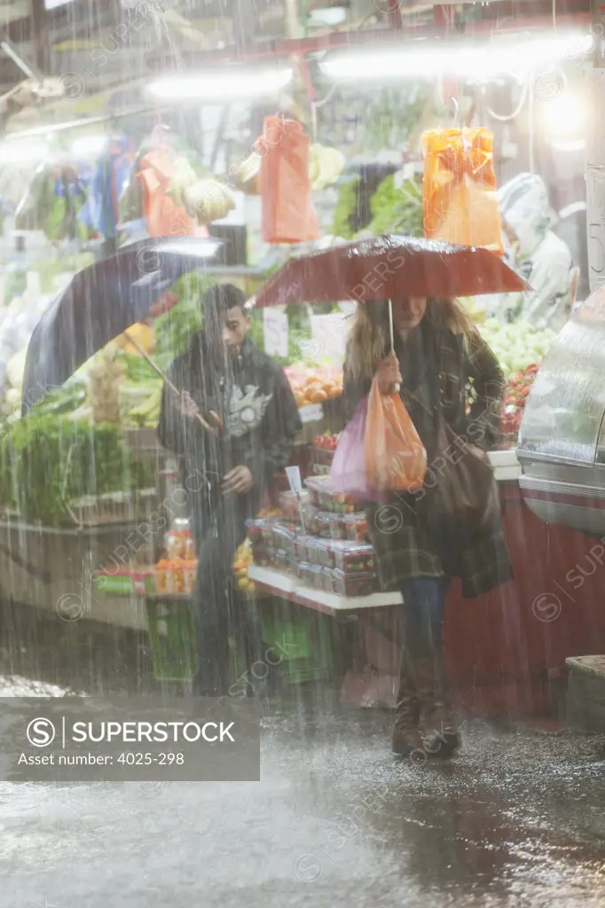 Woman shopping at a fruit stand in the rain, Carmel Market, Tel Aviv, Israel