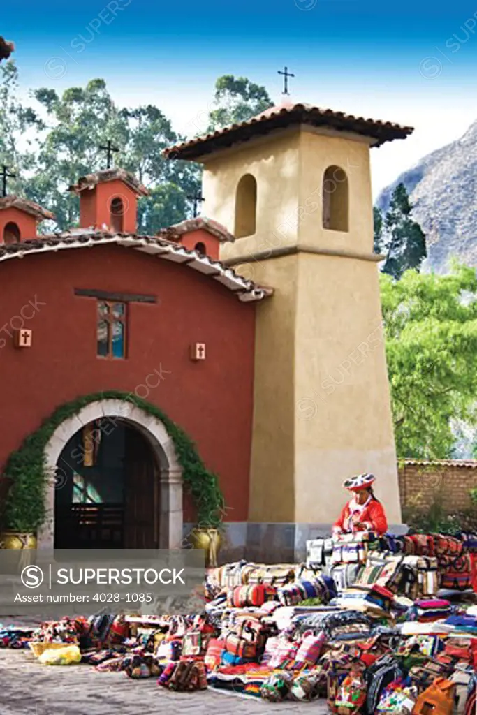 Pisac, Peru, local woman sells her wares in front of a Spanish church in the Sacred Valley.