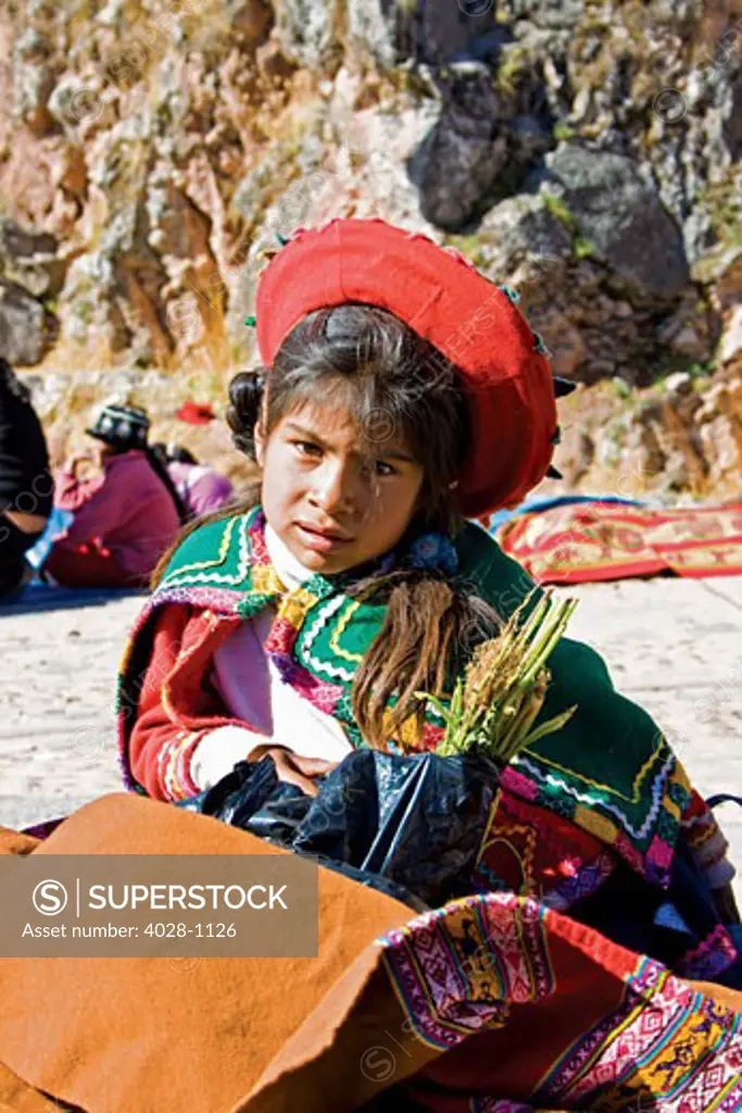 Cusco, Peru, A local girl dressed in traditonal clothing sells textiles at a local market in the Sacred Valley.