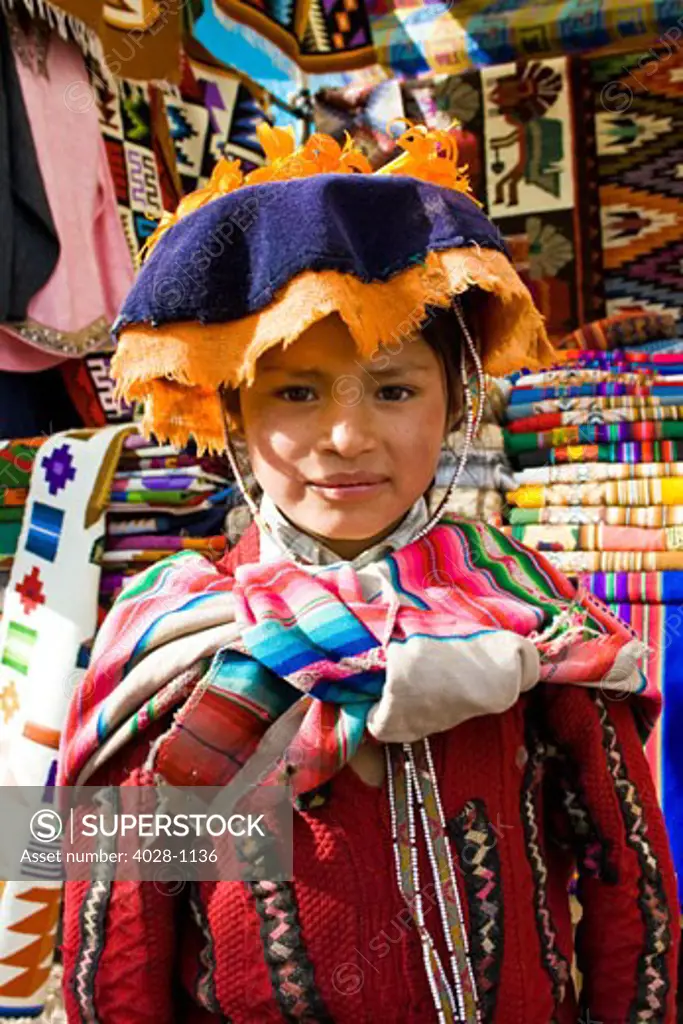 A local girl dressed in traditonal clothing poses in the sacred valley of Peru in the town of Pisac at a local market