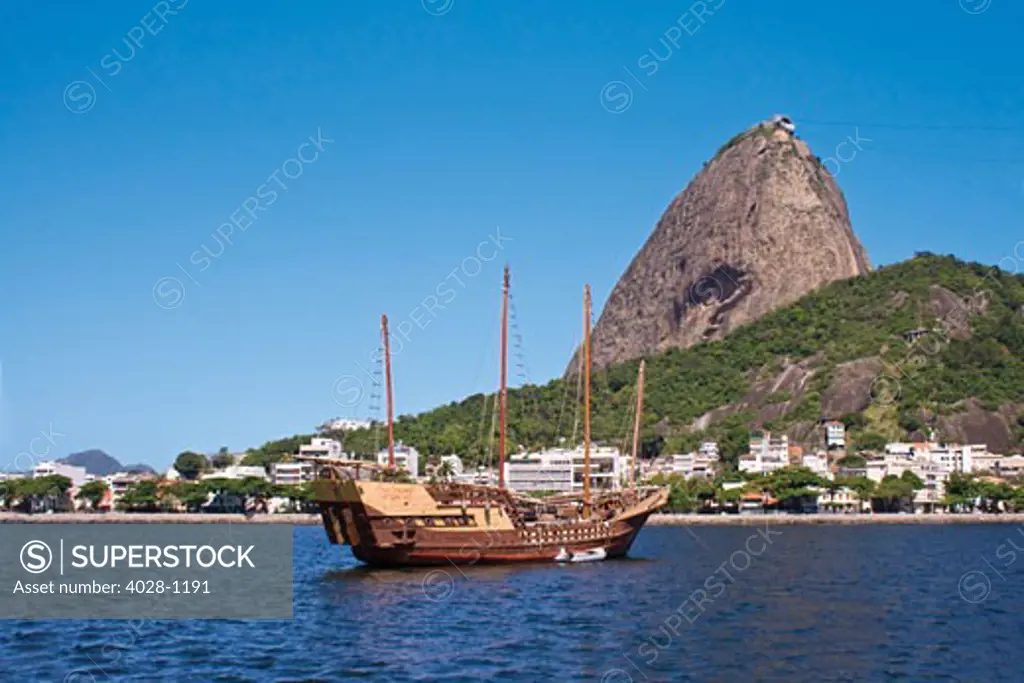Rio de Janeiro, Brazil, View of Sugar Loaf Mountain by boat in Botafogo Bay. An old wooden Tall Ship anchored in front.