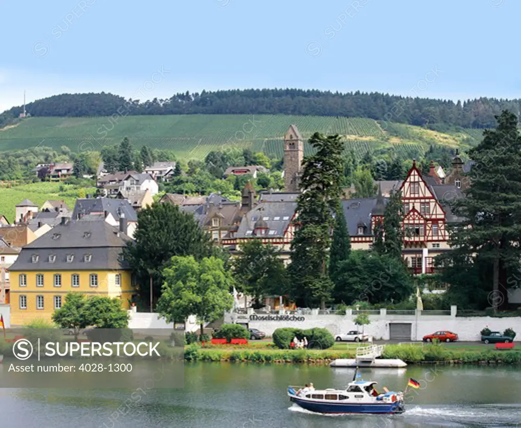 A yacht sails by the town of Traben-Trarbach, Germany along the Mosel River. Moselschlößchen Hotel.