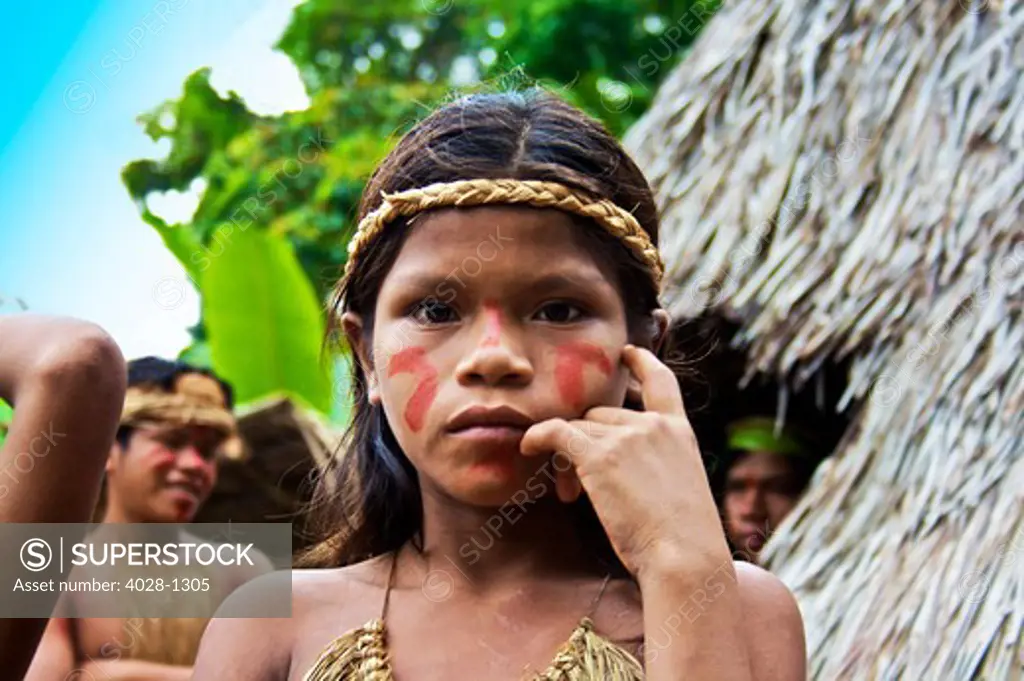 Young girl and other villagers outside of their tribal huts in the Peruvian Amazon Jungle near Iguitos, Peru.
