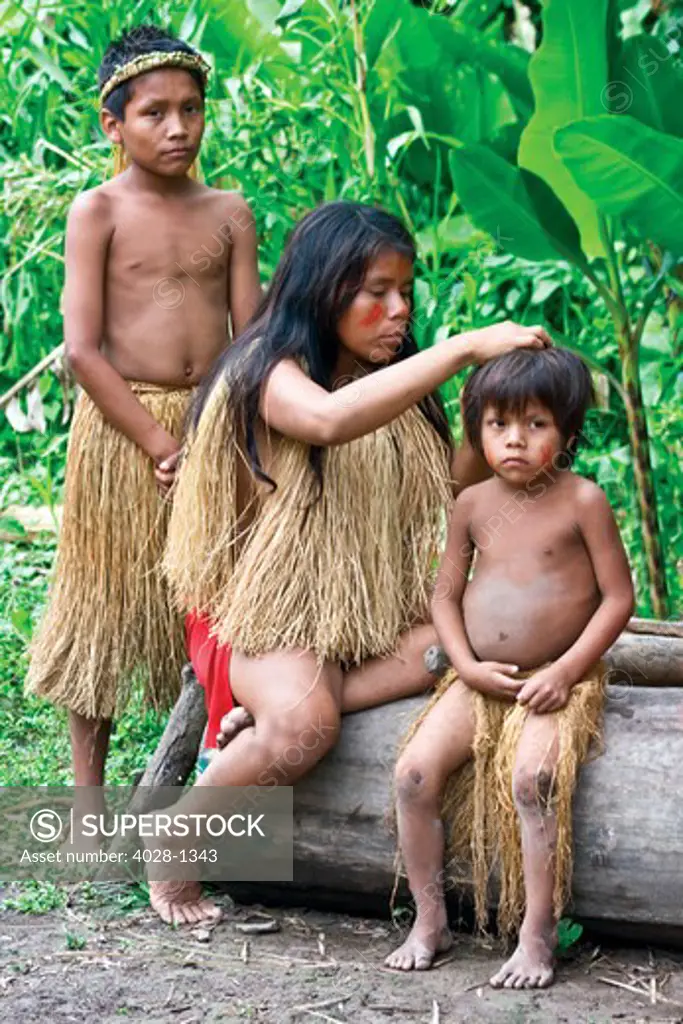 Young boys and  their mother attend to grooming outside of their tribal village in the Peruvian Amazon Jungle near Iguitos, Peru