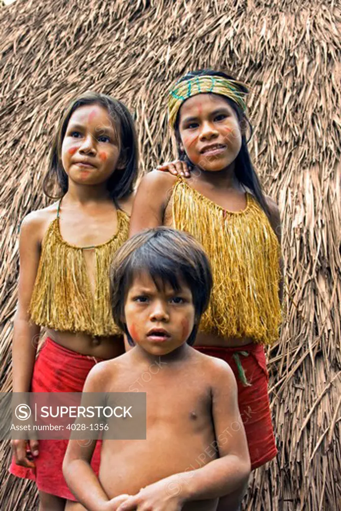 Young girls and  boy stand outside of their tribal hut in the Peruvian Amazon Jungle near Iguitos, Peru
