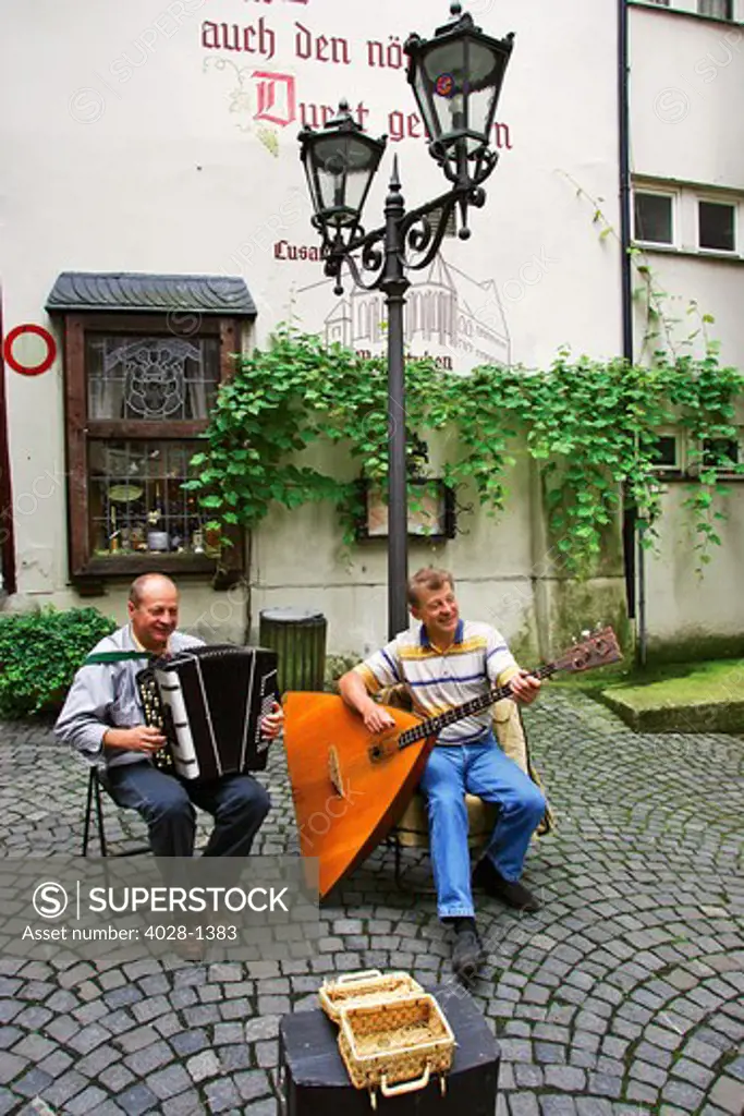 Two German musicians play Traditional Musical instruments, the Balalaika and the accordian for tips in the old town of Traben-Trarbach, Germany in the Rhineland.