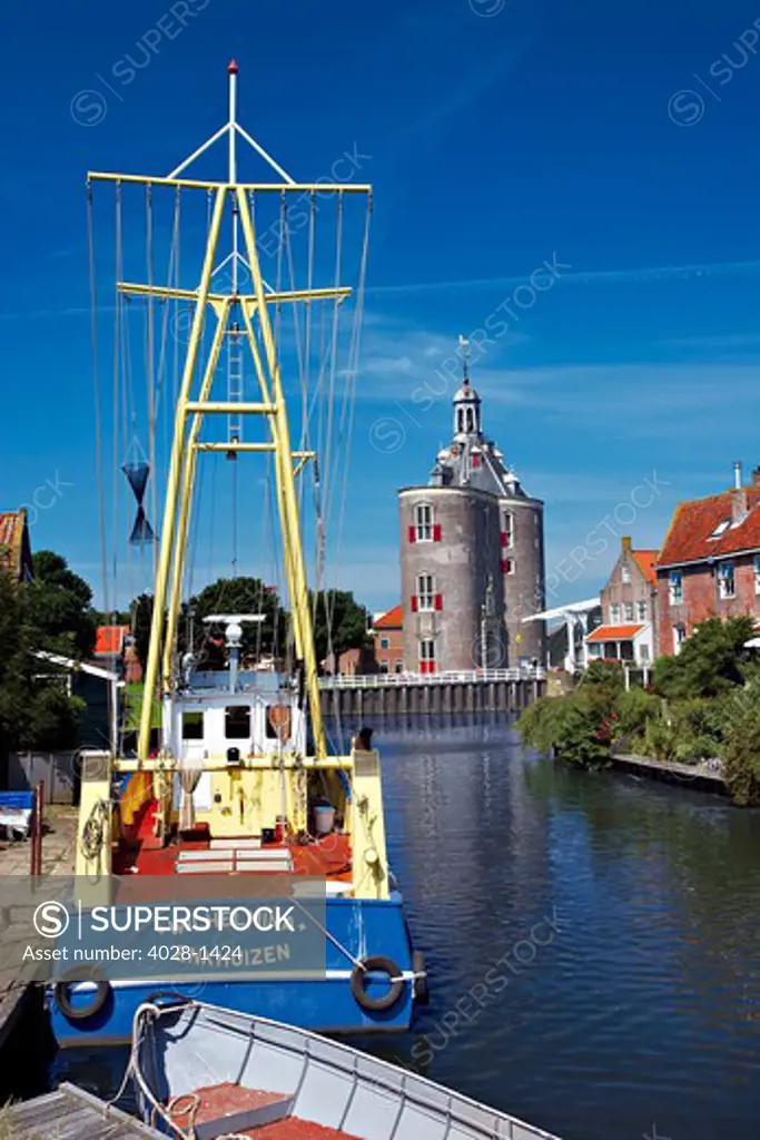 Netherlands, Enkhuizen, Classic Dutch vessels in the canal, Drommedaris Tower in the background.