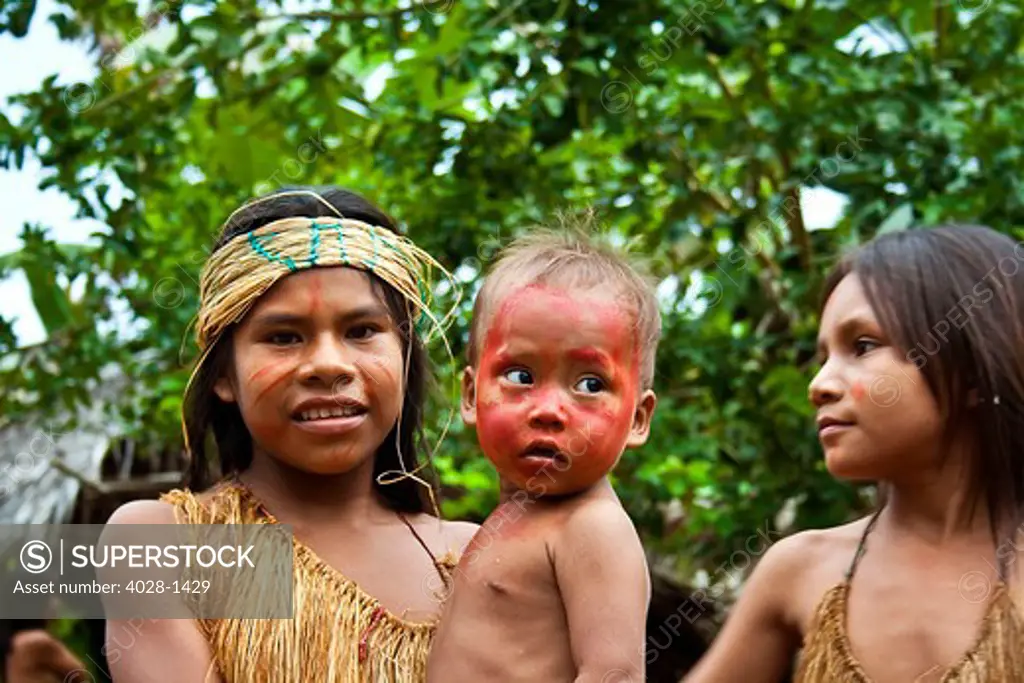 Iquitos, Peru, Amazon Jungle, girls from a Yagua Tribe take care of a younger child in their village.