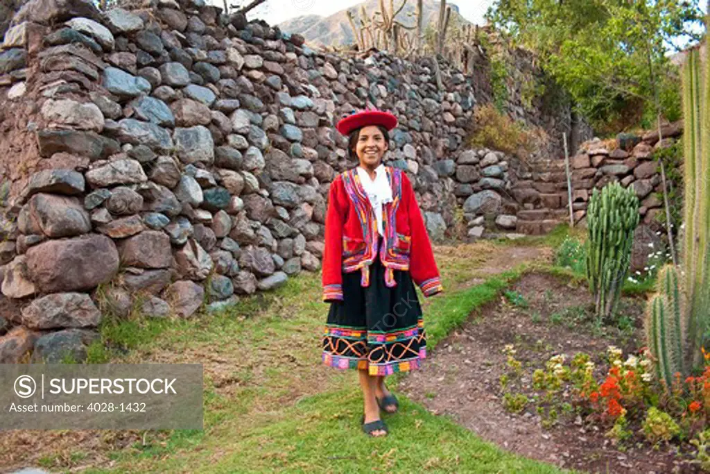 Cusco, Peru, A local girl dressed in traditional clothing walks in the Sacred Valley of Peru near the city of Cusco near a local market.