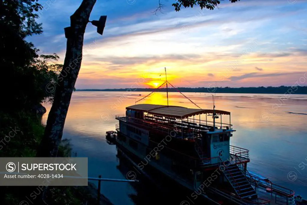Sunset over the Amazon River and jungle and the River Boat, the Amazon Queen, docked in Peru or Brazil