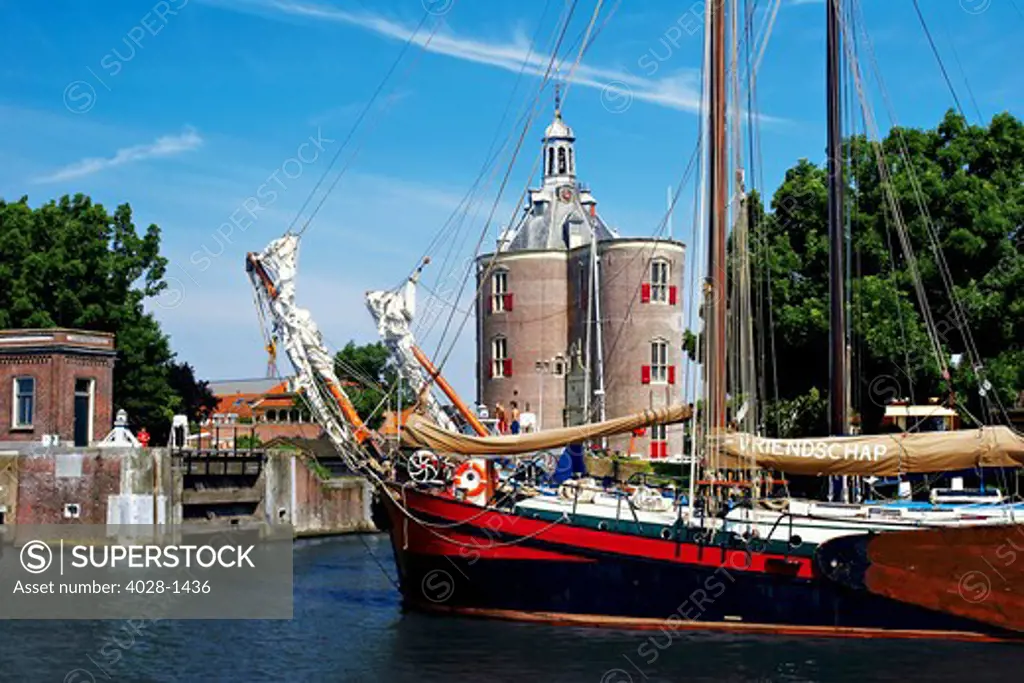 Netherlands, Enkhuizen, Classic Dutch vessels in the canal, Drommedaris Tower in the background.