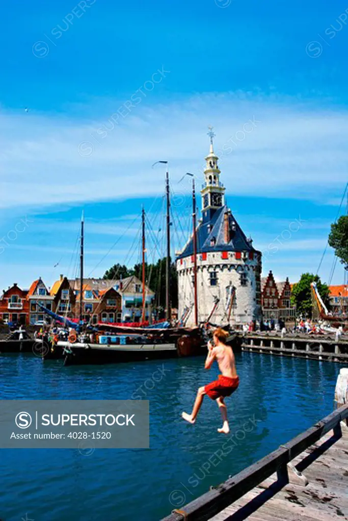 Netherlands, Hoorn, Boys dive and swim in the harbor next to the massive Hoofdtoren.