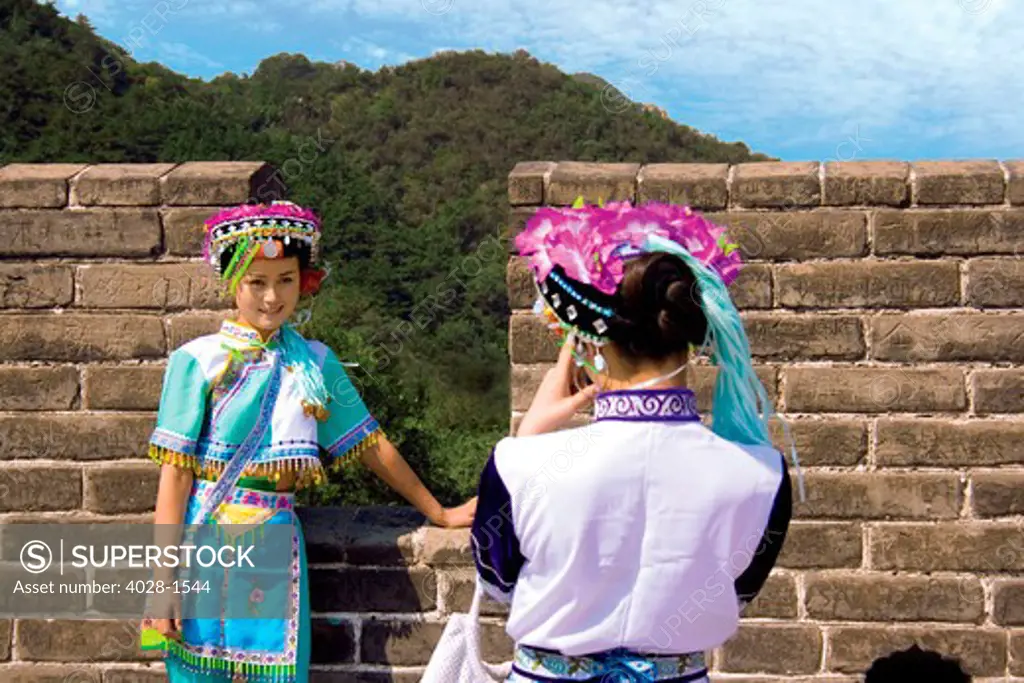 China, Badaling, Great Wall, Two women dressed in traditional minority clothing pose for a digital photo.