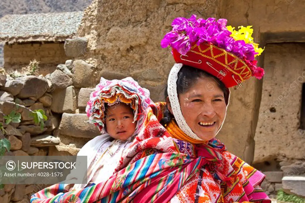 Ollantaytambo, Peru, A woman dressed in traditonal clothing with her baby swaddled in a scarf.
