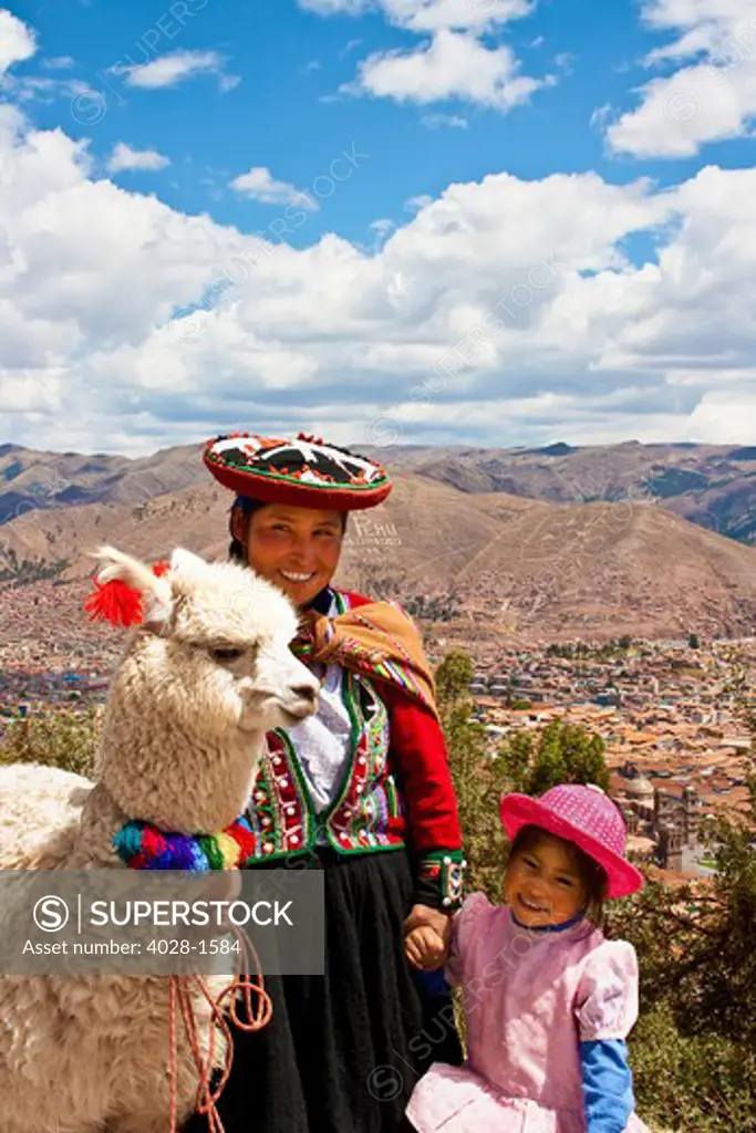 Cusco, Peru, A local woman in traditional clothing leads her llamas through the ruins of Sacsayhuaman.