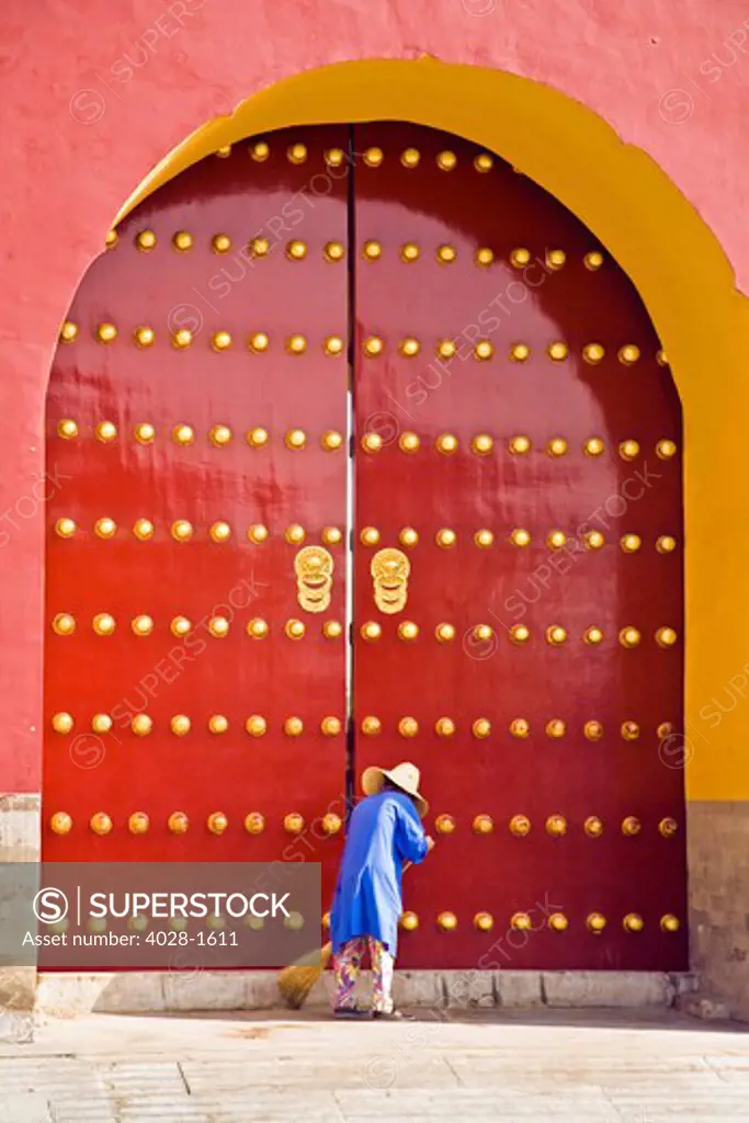 A female Chinese sanitation worker sweeps the entrance to the Forbidden City in Beijing, China
