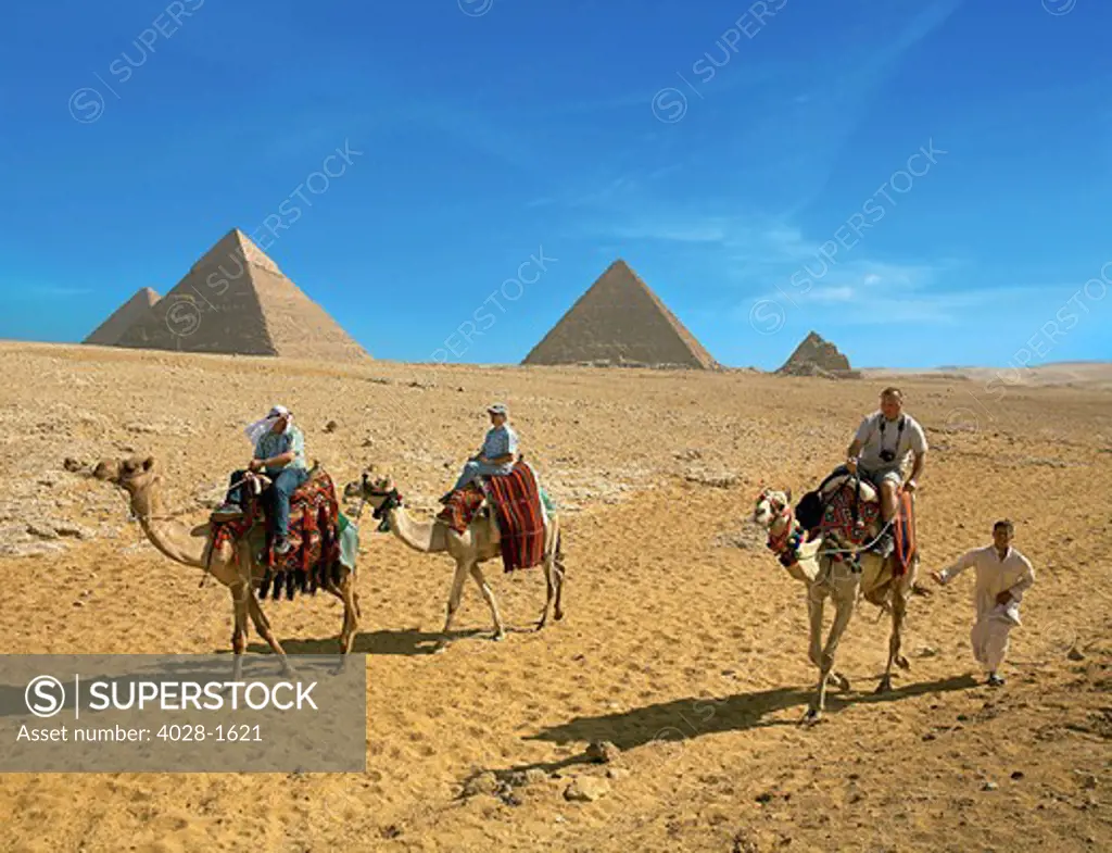 Egypt, Cairo, Giza, Tourists ride with a guide in front of the great pyramids.