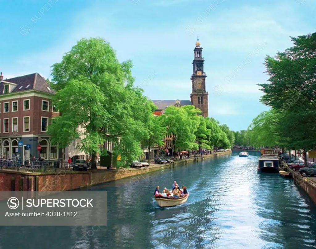 Netherlands, Amsterdam, Boats cruise along a canal with the Zuiderkerk bell-tower in the background. Holland.