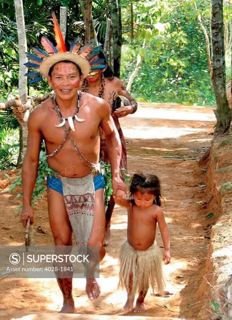 A village elder takes a young girl to their tribal huts in the Peruvian Amazon Jungle near Iguitos, Peru.