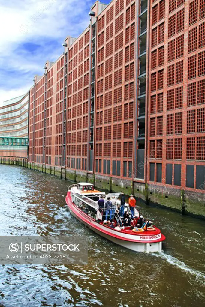 A tour boat moves along the waterfront warehouses and lofts in the Speicherstadt warehouse district of Hamburg, Germany