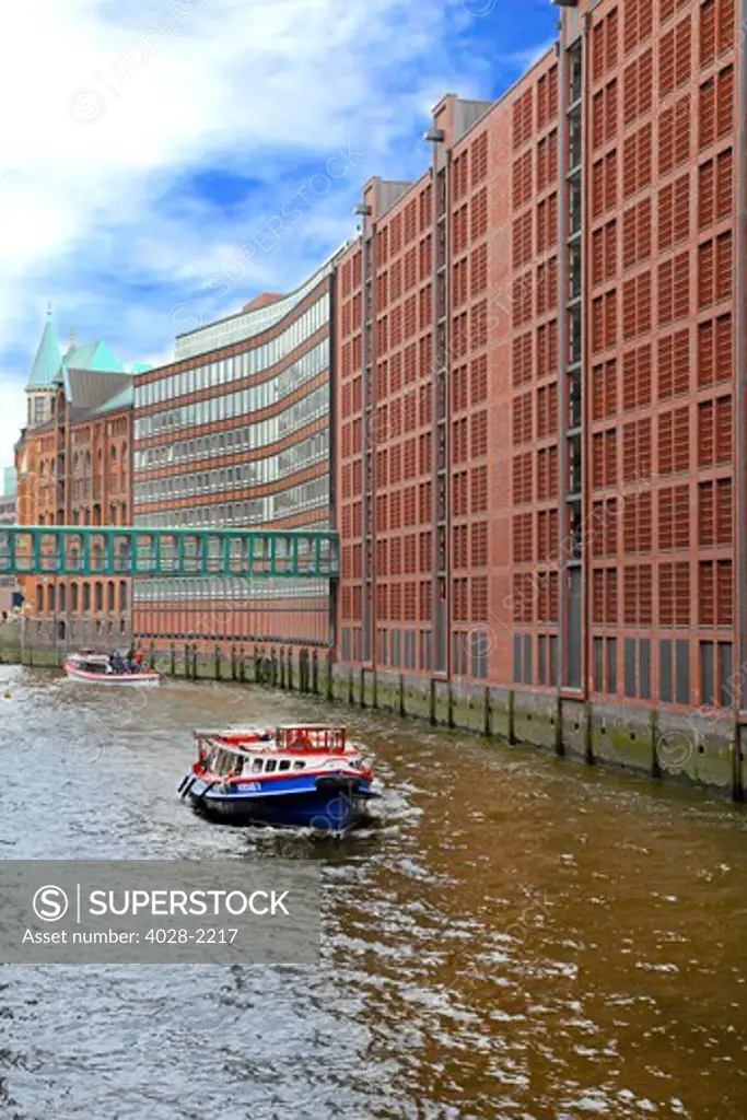 Boats pass along the waterfront warehouses and lofts in the Speicherstadt warehouse district of Hamburg, Germany