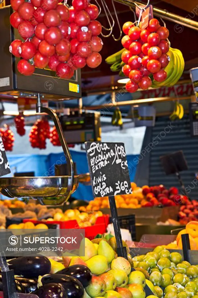 Barcelona, Catalonia, Spain, La Boqueria, La Rambla, vendors display and sell fruits and vegetables in their stall .