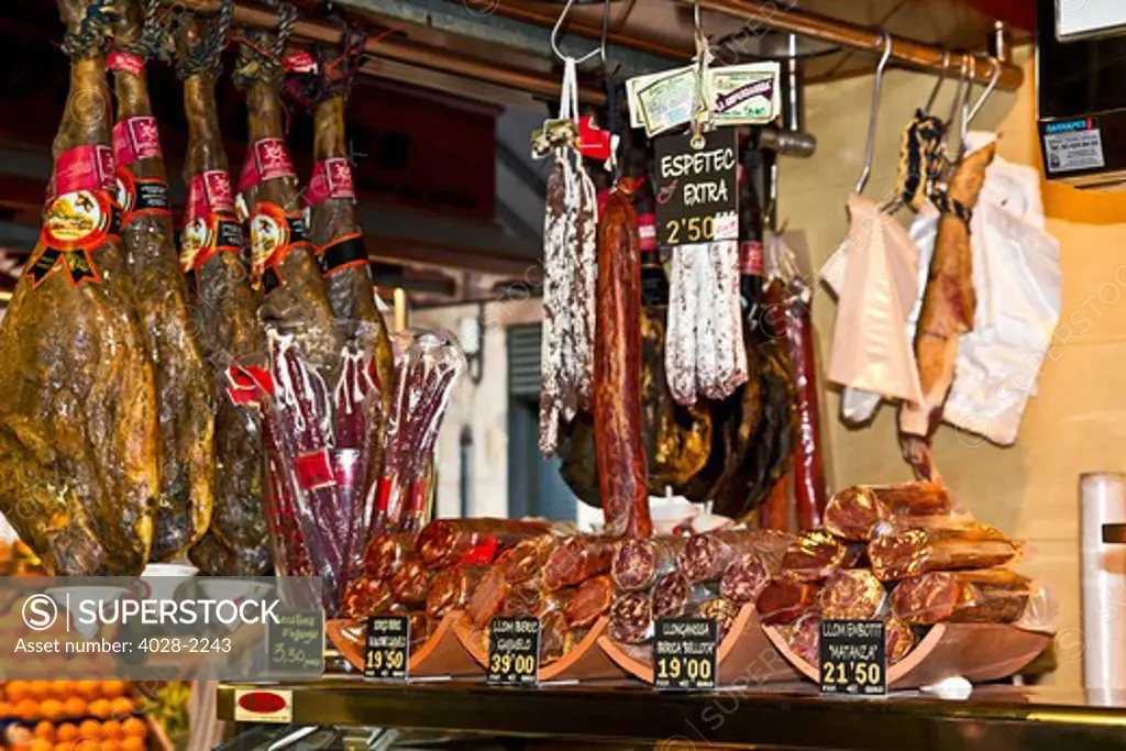 Barcelona, Catalonia, Spain, La Boqueria, La Rambla, vendors display and sell traditional jambon (ham) in their market stall.