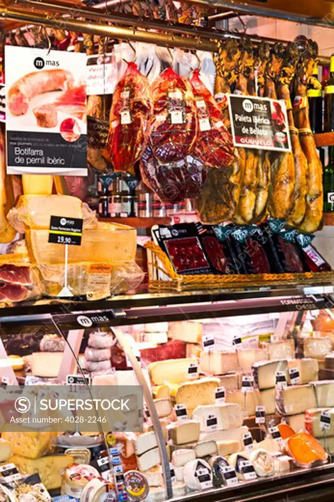Barcelona, Catalonia, Spain, La Boqueria, La Rambla, vendors display and sell meat, cheese and traditional jambon (ham) in their market stall.