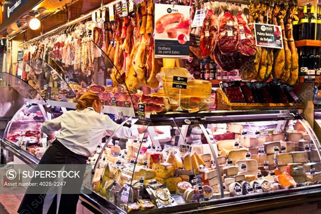 Barcelona, Catalonia, Spain, La Boqueria, La Rambla, vendors display and sell meat, cheese and traditional jambon (ham) in their market stall.