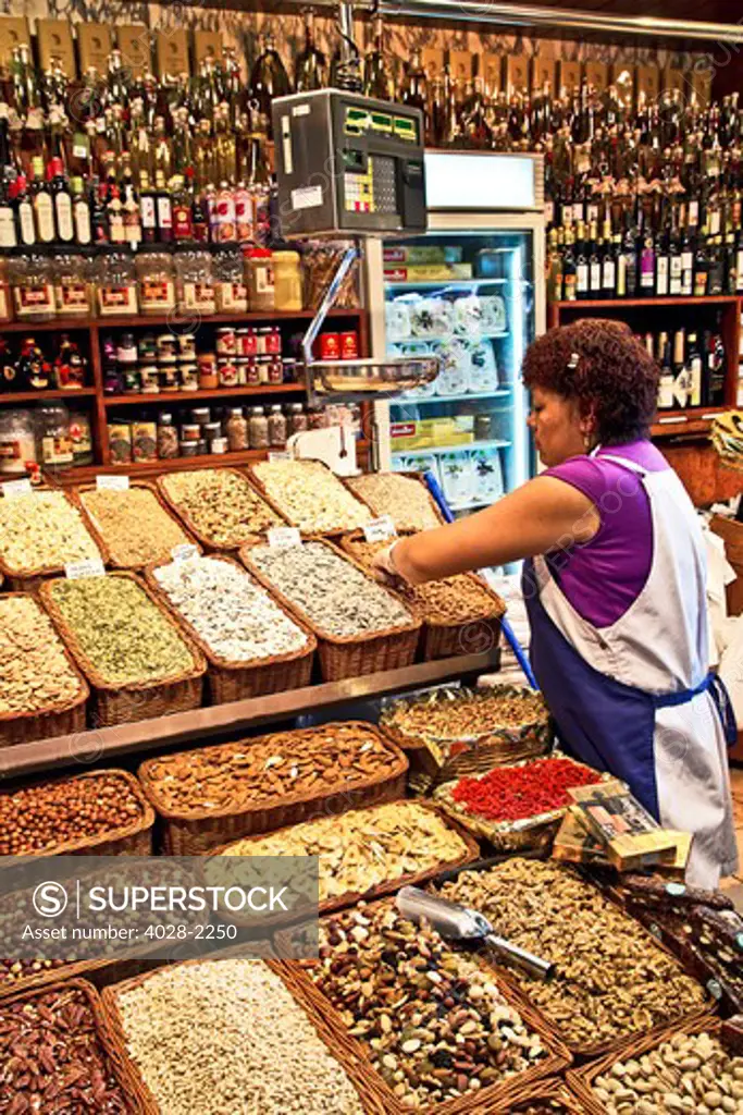 Barcelona, Catalonia, Spain, La Boqueria, La Rambla, vendors display and sell dried fruit, nuts and oils in their market stall.